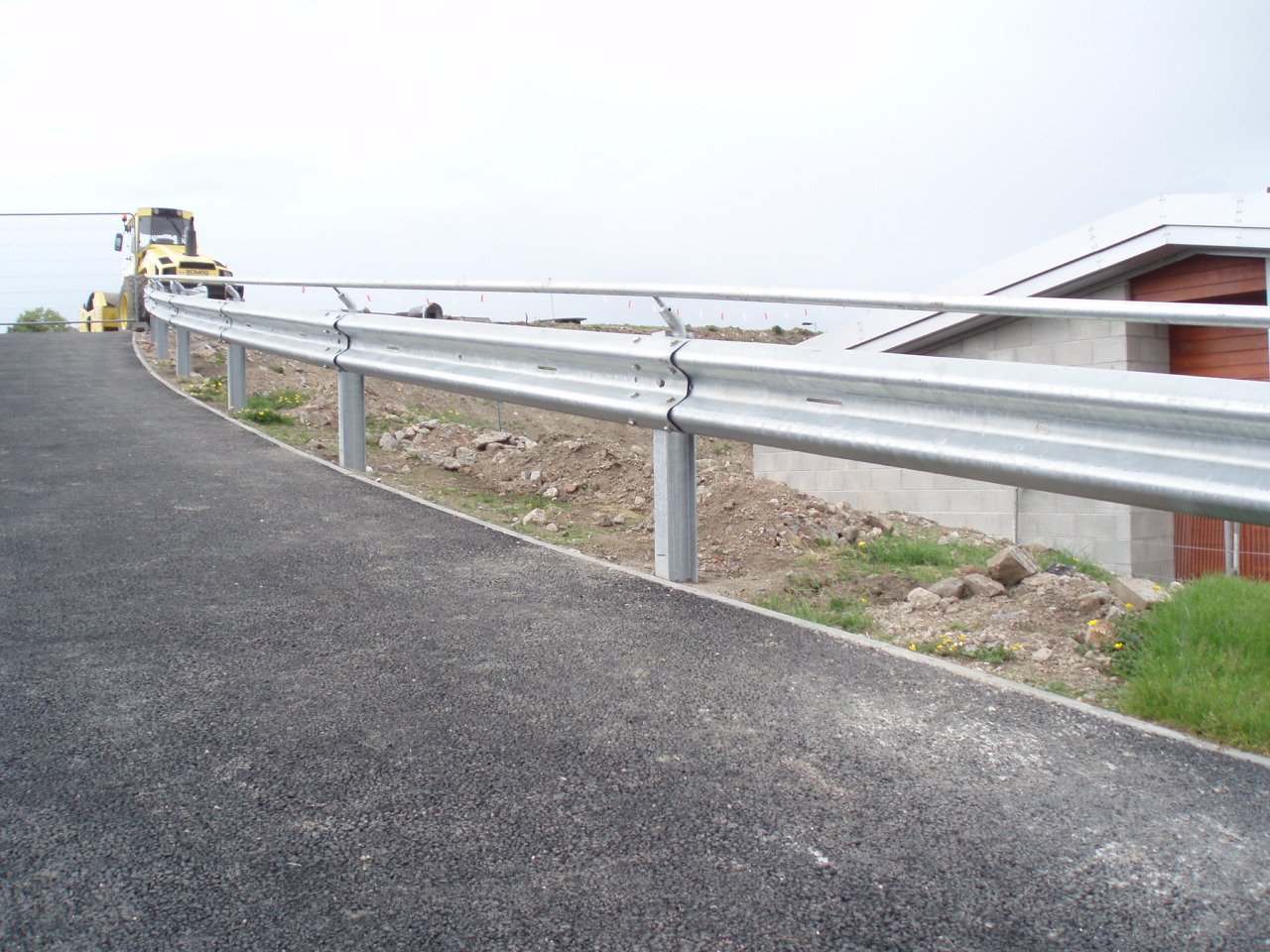 Bespoke deflector rail fitted above corugated beam barrier.